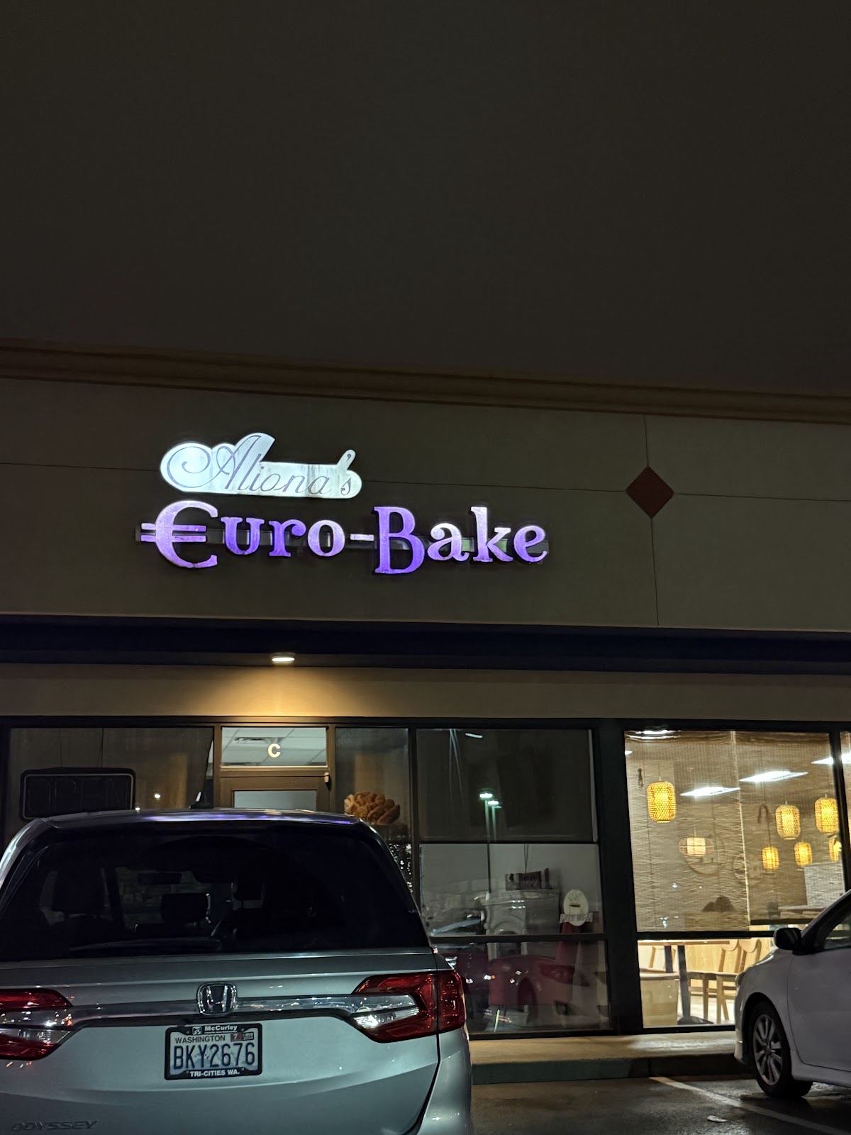 The illuminated Aliona's Euro Bake storefront sign at night in Pasco